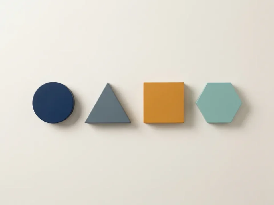 Vier geometrische vormen in marineblauw, grijs, amber en blauwgroen op wit oppervlak, gerangschikt in oplopende progressie.